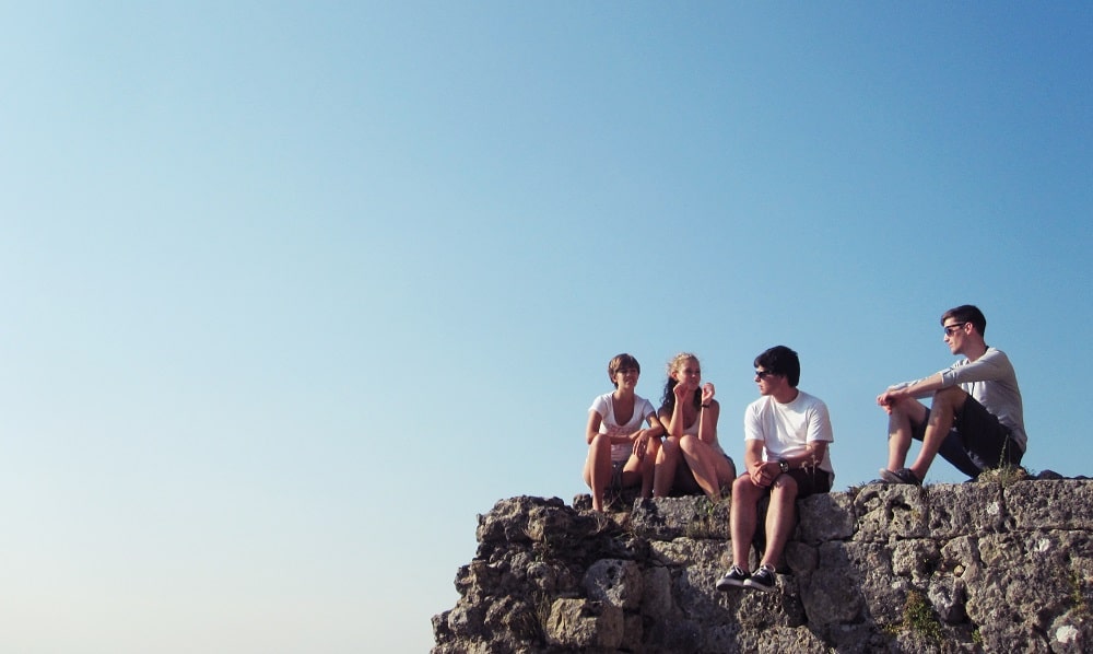 Teens on rock outcrop discuss good money habits for kids