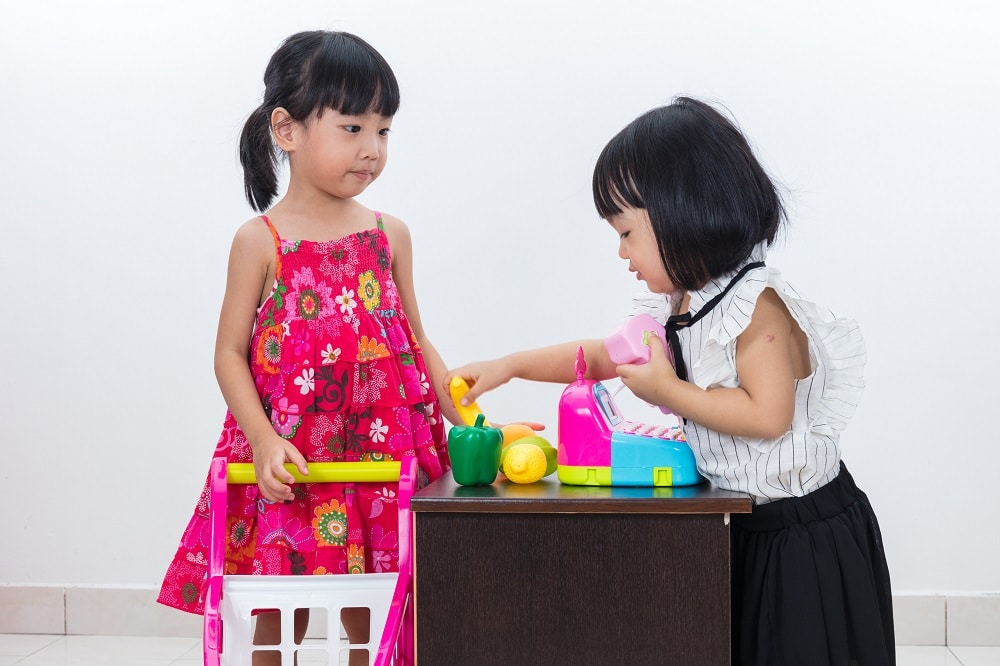 Two young girls playing shop as one of many fun money activities for kids