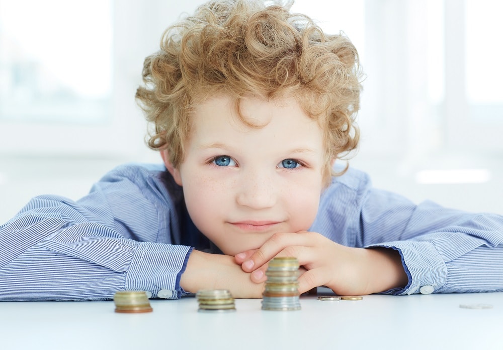 Little boy with piles of coins needs to know savings account options for kids